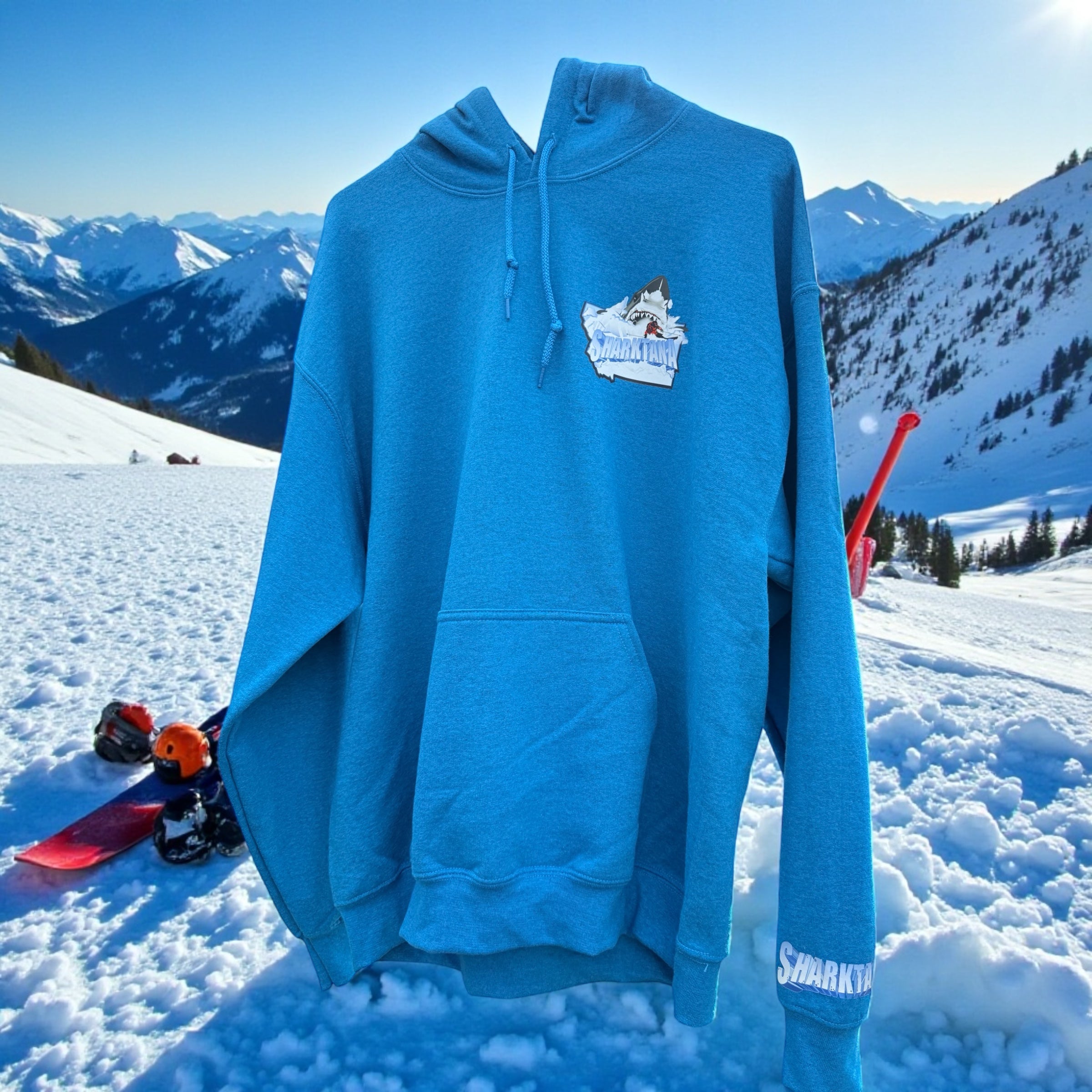 Blue hoodie with a Sharktana logo on a snowy mountain background